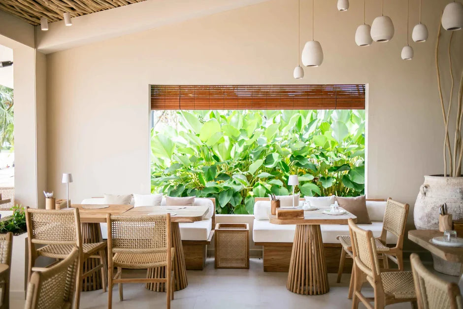 Dining area with natural timber and rattan furniture opening onto lush greenery