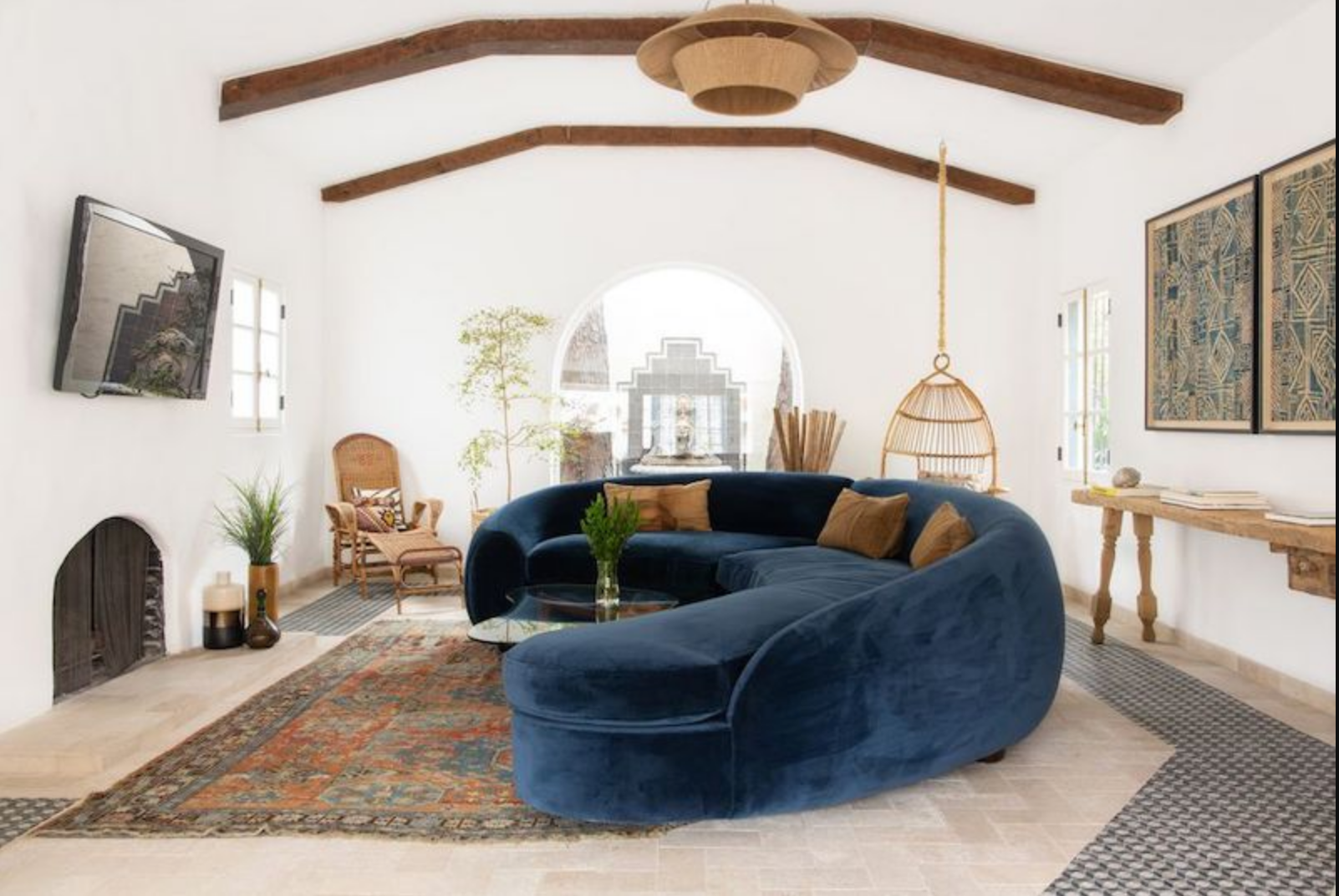 A Mediterranean-inspired living room featuring warm neutral colours, natural stone, textured wall art, wooden furniture and handcrafted ceramics, creating a timeless, elegant and inviting interior inspired by the coastal homes of Southern Europe.