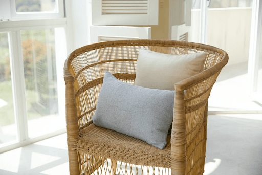 A rattan chair with two pillows on it